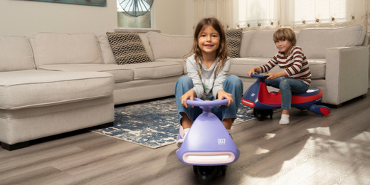 Two children are driving FanttikRide Wiggle Cars in the living room at home