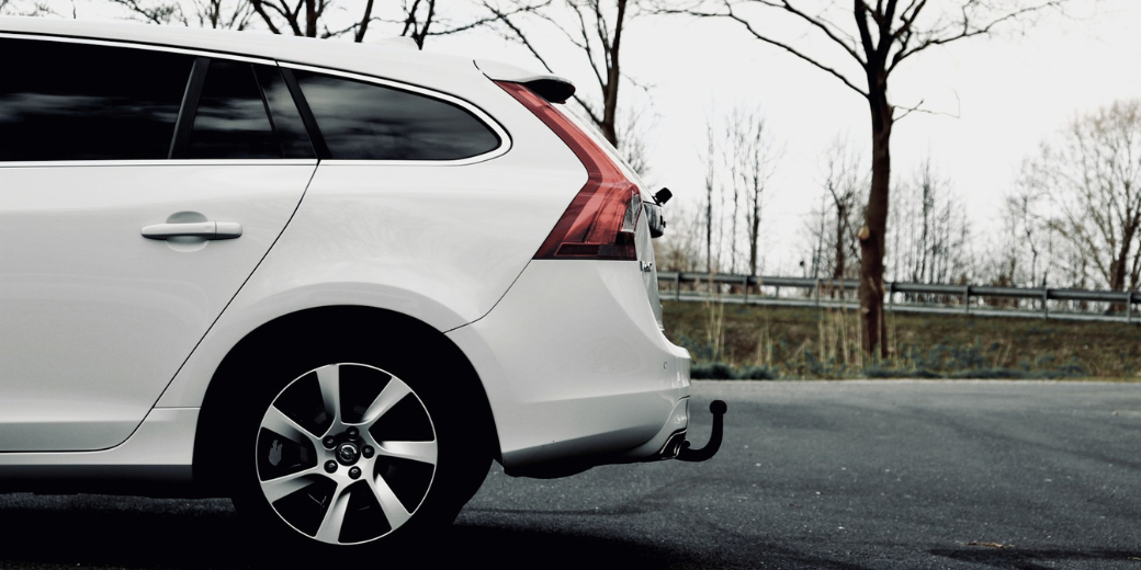 White station wagon with trailer hitch parked on road, ready for seasonal travel with maintained tires.
