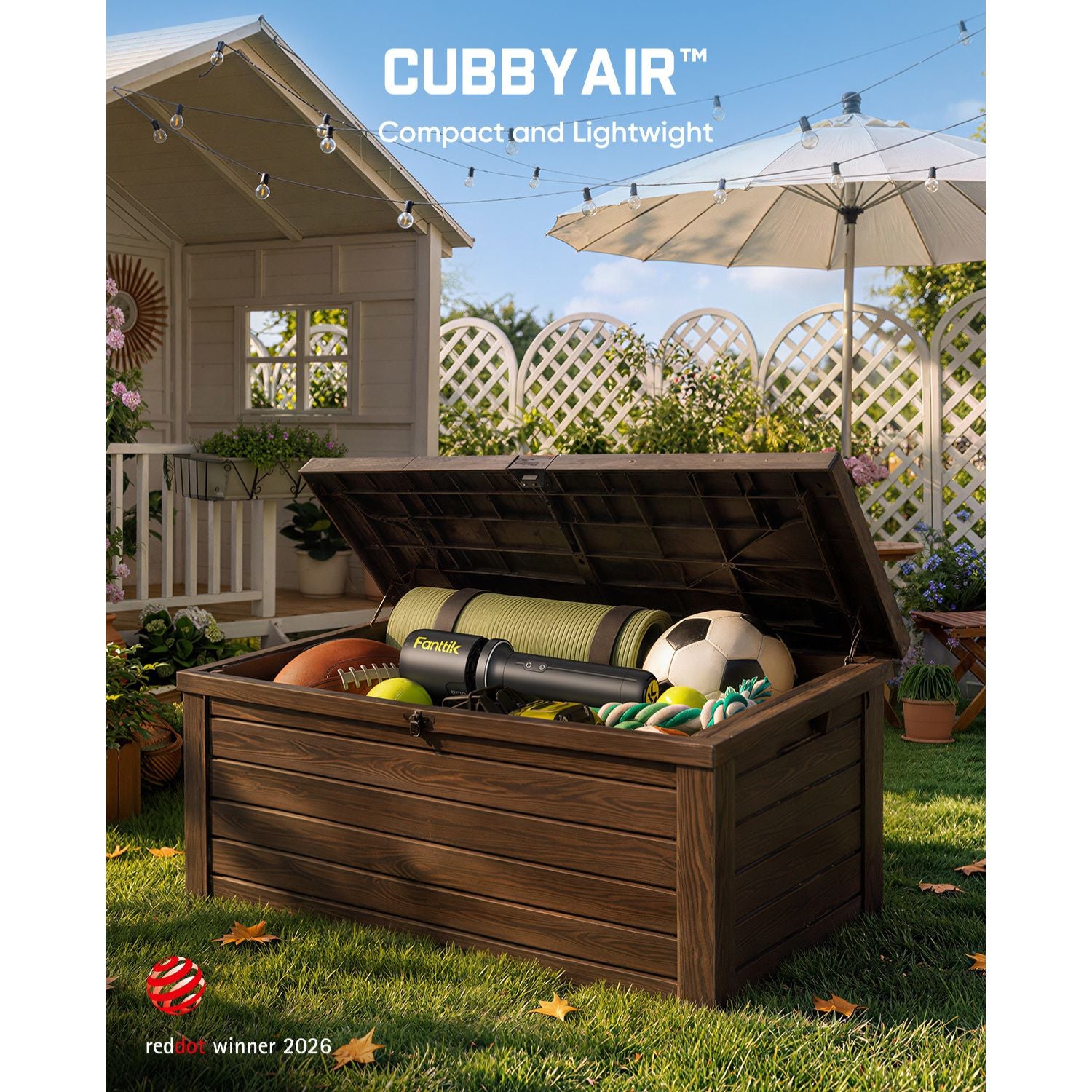 A dark brown wooden storage chest with its lid open, filled with sports balls and a Leaf Blower set in a backyard with a house, patio umbrella, and lawn visible. The text 'CUBBY AIR Compact and Lightweight' appears at the top, and a 'reddot winner 2026' badge appears at the bottom left.