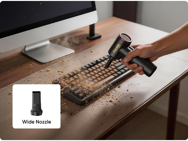 A handheld black mini Electric Air Duster with a gold logo is being used by a person to clean a keyboard and desk, with crumbs being sucked up. The vacuum has a small inset showing a wide nozzle attachment.