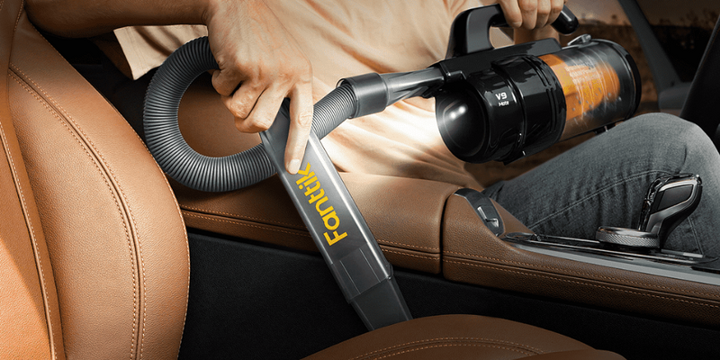 Fanttik cordless handheld portable car vacuum cleaning a leather car seat