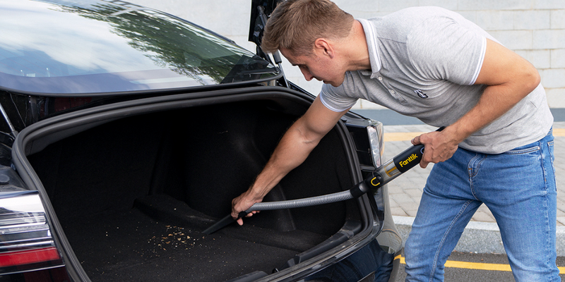 Person cleaning a sedan trunk with a Fanttik cordless car vacuum — compact portable car vacuum for automotive maintenance