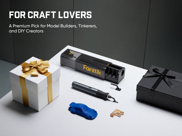 A Fanttik Electric Detail Sander set displayed on a white surface against a dark gray background, including the black rotary tool, a smaller black pen-like accessory, a blue cloth, small metal pieces, a white gift box with a gold ribbon, and a black gift box. Text at the top reads 'FOR CRAFT LOVERS' and 'A Premium Pick for Model Builders, Tinkerers, and DIY Creators.