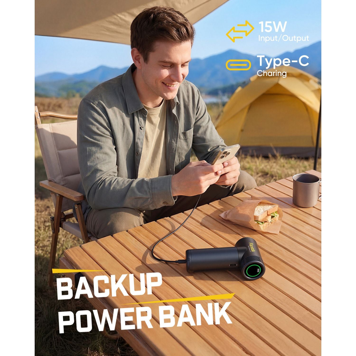 Man using a backup power bank outdoors with camping scenery