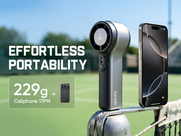 Small GoFlow 11 Apex Handheld Fan with smartphone on a tennis court, emphasizing portability.