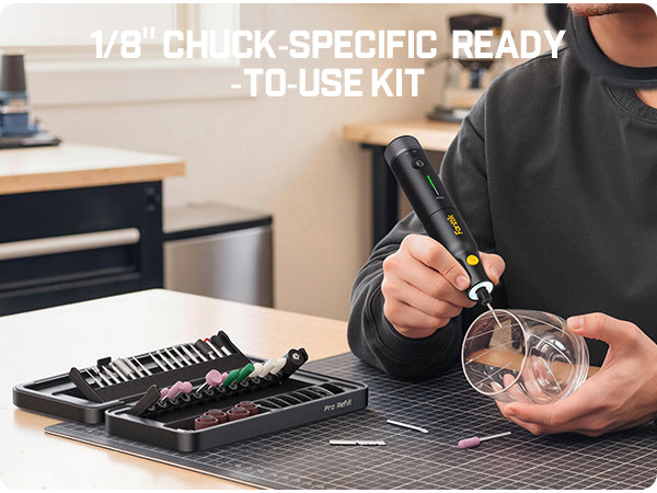 A person using a Rotary Tool to drill into a clear glass cup, with a tray of interchangeable drill bits on a cutting mat in a workshop setting. White text at the top reads '1/8" CHUCK-SPECIFIC READY -TO-USE KIT'.