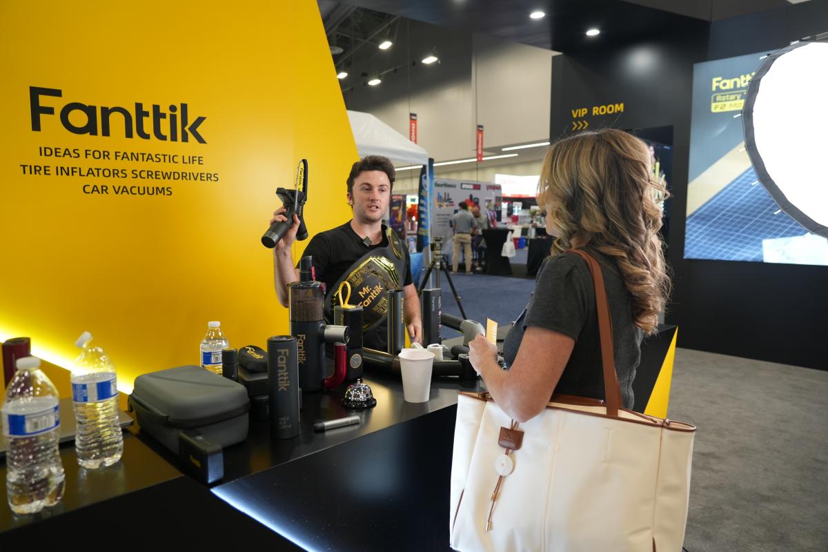 Person interacting with a display at an event with 'Fanttik' branding.