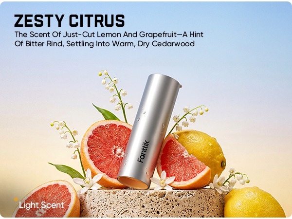 A silver cylindrical scented candle by Fantik stands upright on a stone base, surrounded by citrus slices, grapefruit, lemons, and white flowers. Large text at the top reads 'ZESTY CITRUS' with a scent description, and 'Fantik' is printed on the candle.